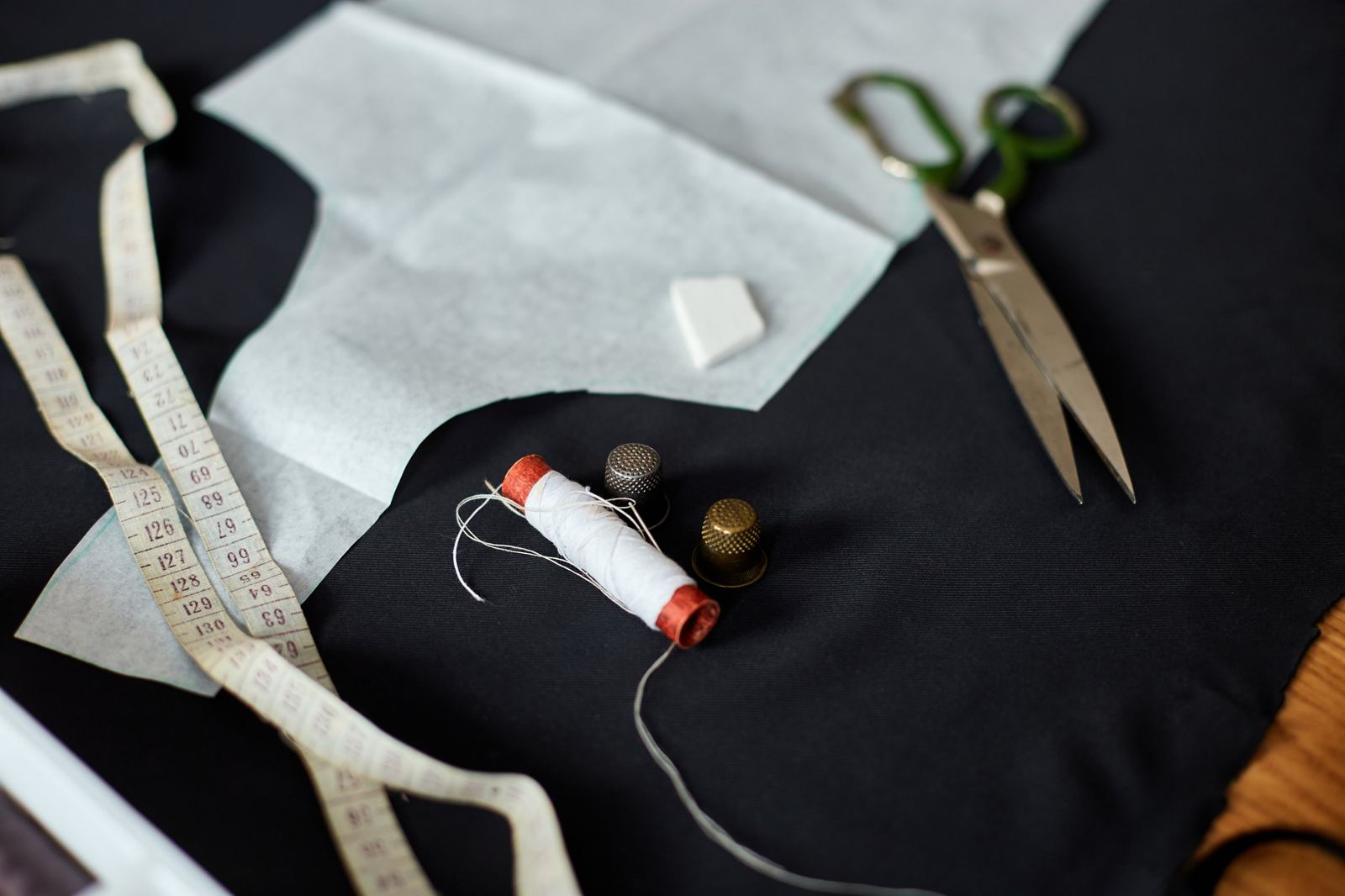 Tape measure, thread, thimbles and tailor's scissors on fabric