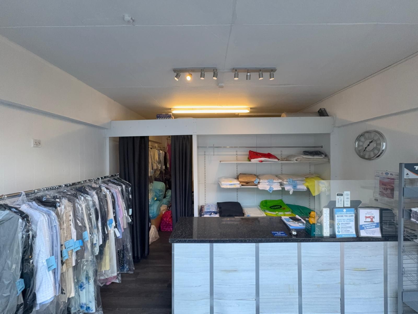 Inside the shop: the counter and freshly cleaned garments on the rail, each with its ticket