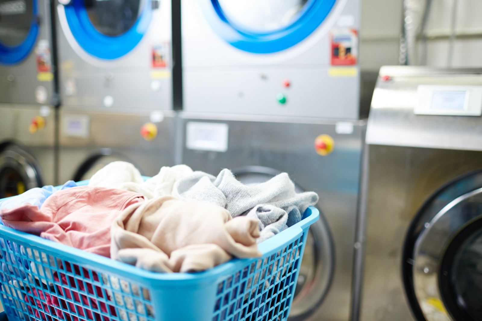 Basket of laundry in front of commercial washing machines